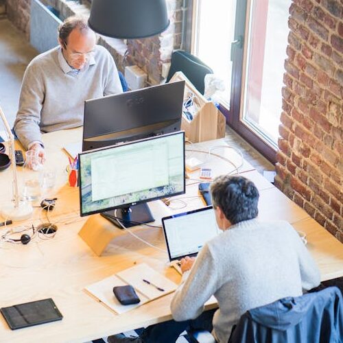 pexels-photo-2451646-2451646 Bird's-eye view of a modern office with professionals collaborating on laptops and monitors.