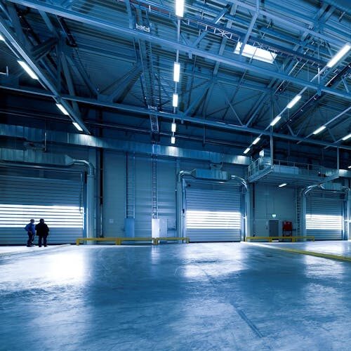 pexels-photo-257636-257636 Wide view of an empty modern warehouse with industrial lighting and trucks.