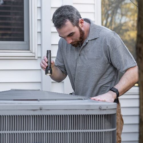 pexels-photo-32497161-32497161 A technician inspects an outdoor HVAC unit for maintenance.