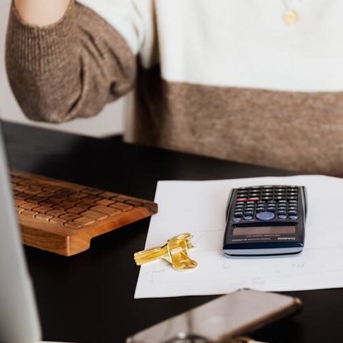 pexels-photo-4491441-4491441 A business desk setup with a calculator, papers, and a keyboard, reflecting a work environment.