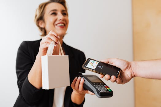Smiling cashier handles a purchase with a contactless mobile payment in a modern shop.
