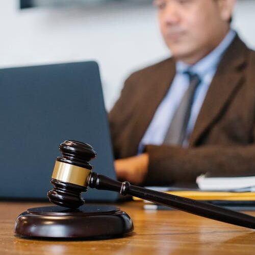 pexels-photo-5668772-5668772 Crop concentrated Asian male judge in formal clothes sitting using modern netbook while working in law office